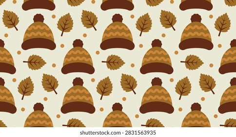 A repeating autumn pattern with brown knit winter hats, pom-poms, and dry autumn leaves on a light background.