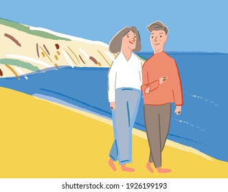 Retired elderly couple walking along the beach enjoying life