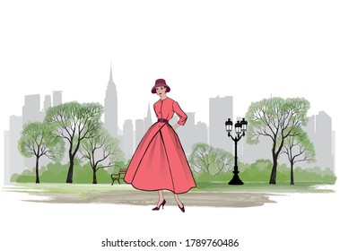 Retro fashion dressed woman (1950s 1960s style) in city park landscape. Stylish young lady in vintage clothes in spring city garden. Spring fashion silhouette from 60s. Park Urban cityscape skyline