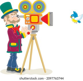 Retro filmmaker in a top hat with his old camera making a film with a flying small bird, vector cartoon illustration isolated on a white background