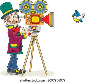 Retro filmmaker in a top hat with his old camera making a film with a flying small bird, vector cartoon illustration isolated on a white background