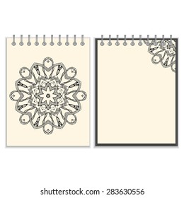 Ring-bound notebook with hand drawn black round pattern including snakes elements on white cover and pages