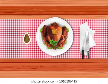 Roasted turkey bird on white plate with fork and knife on wooden table