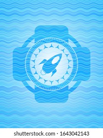 rocket icon inside sky blue water wave style badge.