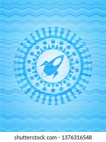 rocket icon inside water wave style badge.