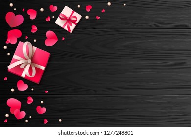 Romantic background with paper hearts and present boxes on the wooden surface.