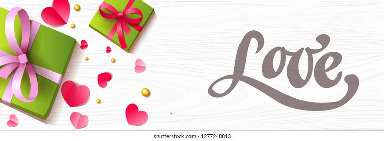 Romantic background with paper hearts present boxes and lettering on the wooden surface.
