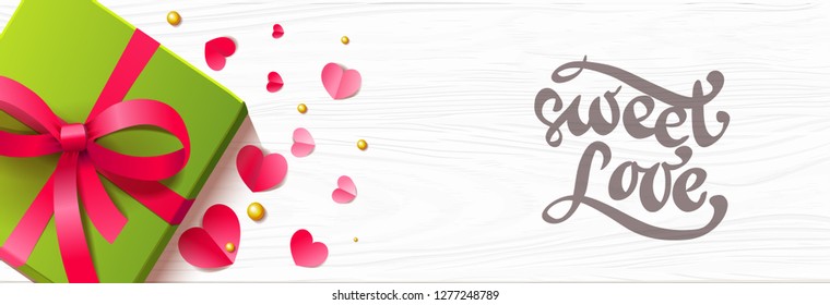 Romantic horizontal background with paper hearts present box and lettering on the wooden surface.