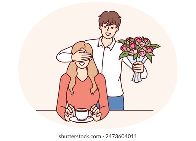 Hombre romántico con ramo cierra los ojos de la novia, con ganas de hacer la sorpresa y dar flores favoritas. Romántico novio llegó a la cita con flores para la novia tomando café en el café o bar