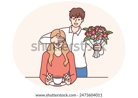Romantic man with bouquet closes girlfriend eyes, wanting to make surprise and give favorite flowers. Romantic groom came on date with flowers for bride drinking coffee in cafe or bar