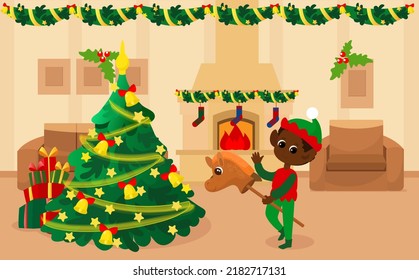 In the room near the Christmas tree there is a happy elf boy on a toy horse. Home for Christmas or Christmas Eve inside. The room has a fireplace with fire, an armchair and a sofa. 