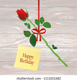 A rose flower is hanging on a red ribbon with a bow. Yellow sheet of paper for notes. Sticker.Greeting card or invitation for a holiday. Empty place for text or advertising. Vector on wooden back