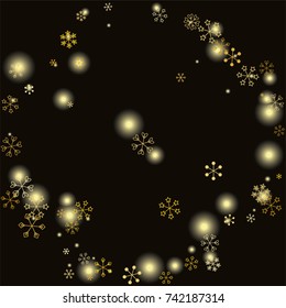 Round frame or border Christmas background with random scatter falling gold snowflakes and yellow blurred lights isolated on black.