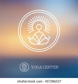 Round outline yoga logo with abstract symbol of man in meditation pose on blurred background