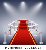Round podium with red carpet and barrier rope in glow of spotlights