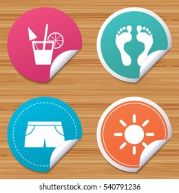 Round stickers or website banners. Beach holidays icons. Cocktail, human footprints and swimming trunks signs. Summer sun symbol. Circle badges with bended corner. Vector