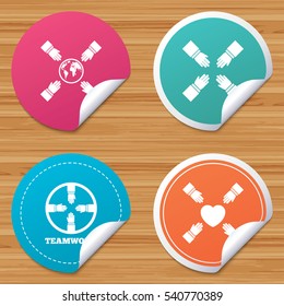 Round stickers or website banners. Teamwork icons. Helping Hands with globe and heart symbols. Group of employees working together. Circle badges with bended corner. Vector