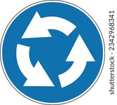 Roundabout direction sign. Mandatory sign. Round blue sign. Drive around the flowerbed (central island) in the direction shown by the arrows at the roundabout. Road sign.