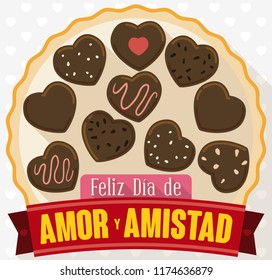 Rounded box with delicious chocolate hearts with tasty flavors and greeting ribbon to celebrate Day of Love and Friendship (written in Spanish).