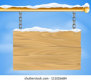 A rustic wooden snow covered winter Christmas sign hanging suspended from a brass metal pole with the blue sky in the background