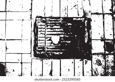 A rusty metal grate on a tiled floor with a single leaf resting on it, surrounded by concrete tiles. 