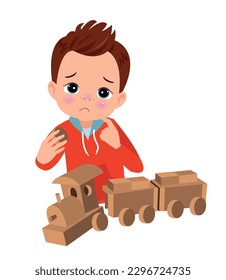 Sad boy with wooden train cars on a white background
