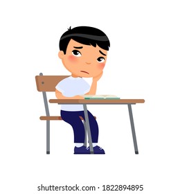 Sad elementary school student. Unhappy little Asian schoolboy sitting at table and no reading book. Boy in school uniform does not want to do his homework