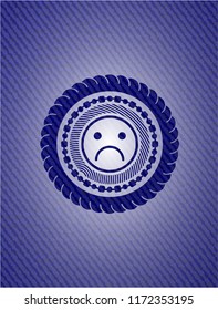sad face icon inside badge with denim background