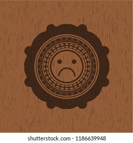 sad face icon inside badge with wood background