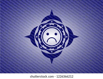 sad face icon inside badge with jean texture