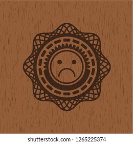 sad face icon inside badge with wood background