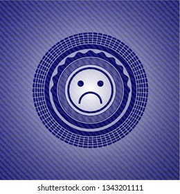 sad face icon inside badge with denim background