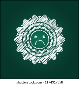 sad face icon inside chalkboard emblem written on a blackboard