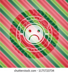 sad face icon inside christmas colors badge.