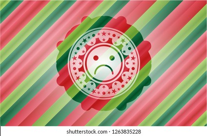 sad face icon inside christmas colors badge.