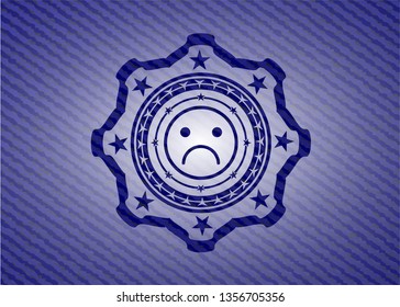 sad face icon inside emblem with denim texture