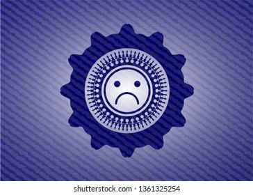 sad face icon inside emblem with denim texture