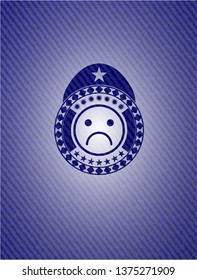 sad face icon inside emblem with jean texture