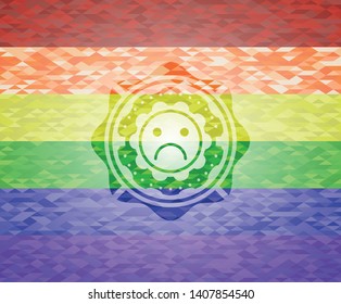 sad face icon inside emblem on mosaic background with the colors of the LGBT flag