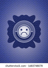 icono de cara triste dentro del emblema con textura de denim