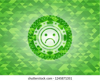 sad face icon inside green emblem with mosaic background
