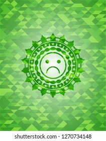 sad face icon inside green emblem with mosaic ecological style background
