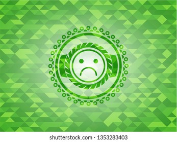 sad face icon inside green emblem. Mosaic background