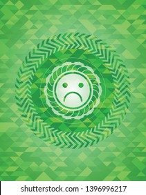 sad face icon inside green emblem with mosaic background