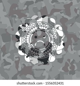 sad face icon inside grey camouflaged emblem