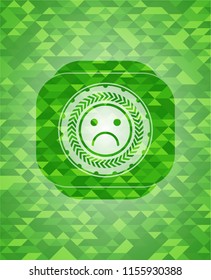 sad face icon inside realistic green mosaic emblem