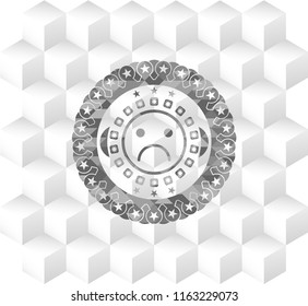 sad face icon inside realistic grey emblem with cube white background