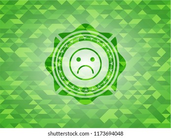 sad face icon inside realistic green mosaic emblem