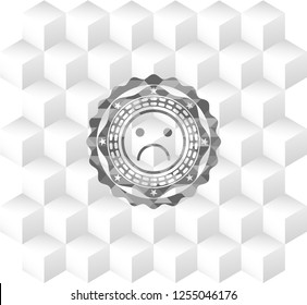 sad face icon inside realistic grey emblem with geometric cube white background