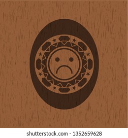 sad face icon inside realistic wood emblem